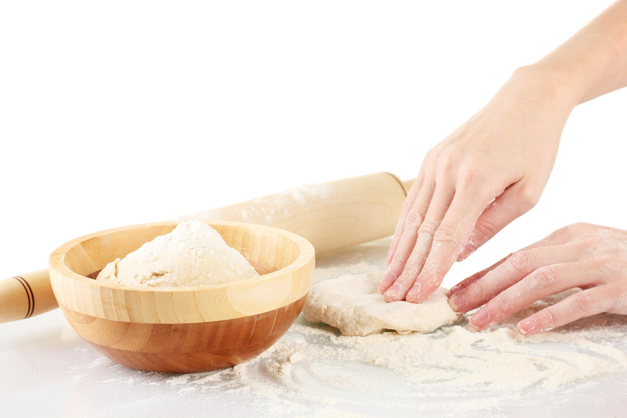 Close-up of hands kneading dough in a bright kitchen
